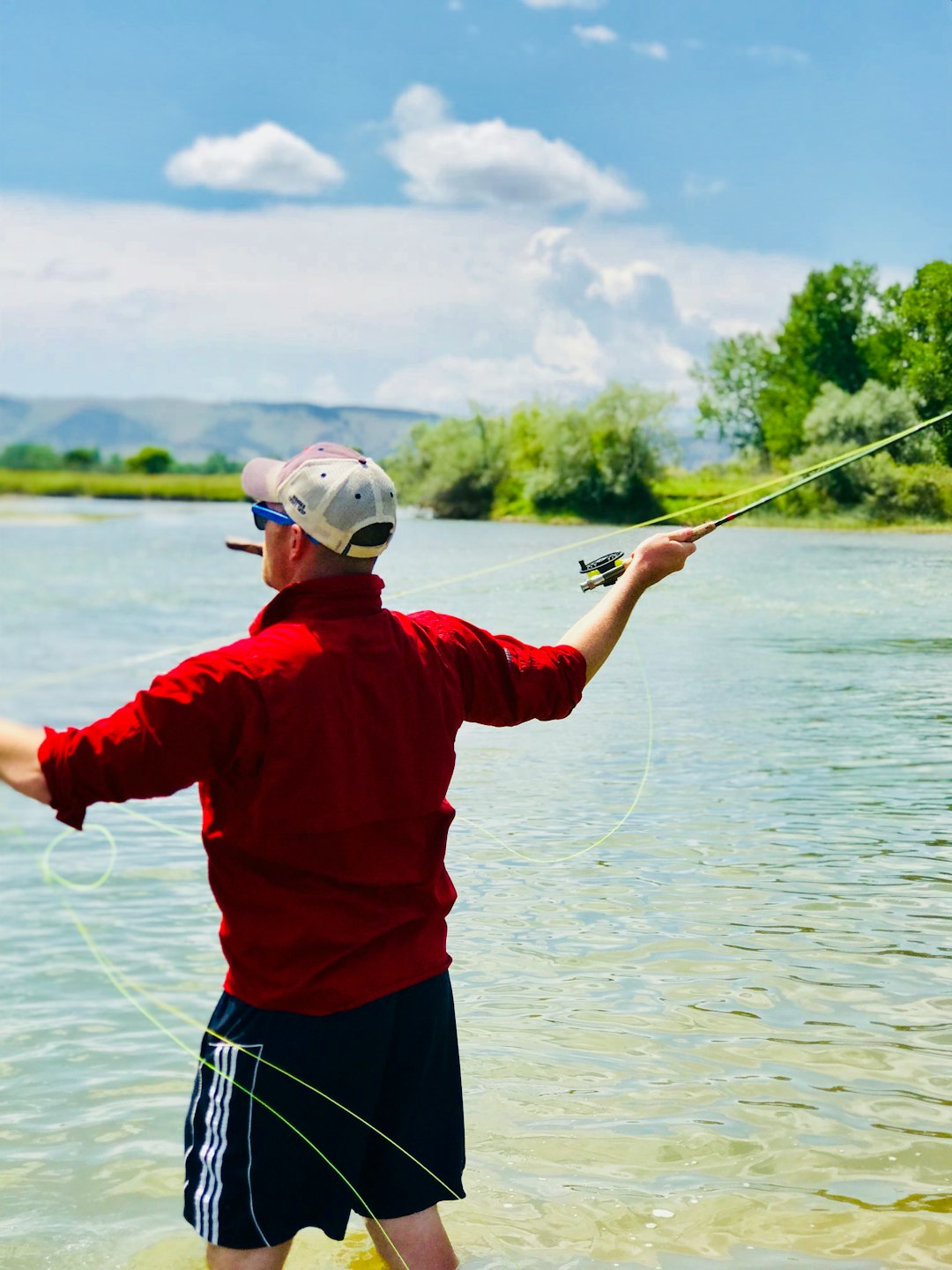 Close-up of an angler holding a fishing rod by the water